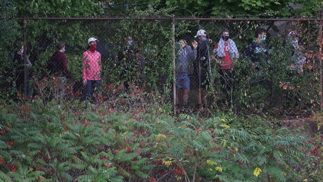 With limited seating in the stands of the Woburn at Arlington boys soccer game because of the COVID-19 restrictions, some spectators chose to hang out at the fence along the Minuteman Bikeway Saturday afternoon, Oct. 3, 2020.