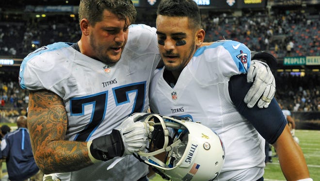 Titans tackle Taylor Lewan (77) hugs quarterback Marcus Mariota (8) after defeating the Saints 34-28 in overtime Sunday.