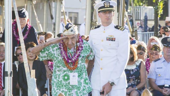 Pearl Harbor survivor, Al Rodrigues salutes for the audience during a ceremony at the Arizona Memorial in Honolulu, Hawaii.