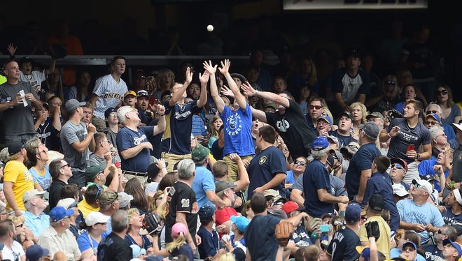 Catching a foul ball is fun but getting hit by one, not so much. Here, fans reach for a foul ball during the first inning of a game between the Milwaukee Brewers and the Cincinnati Reds at Miller Park on Aug. 13, 2017.