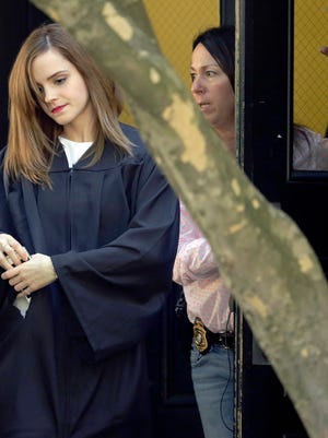 In this Sunday, May 25, 2014 photo, actress Emma Watson, left, is accompanied by a woman wearing a badge and with the handle of a handgun visible at her side, as she walks on campus following commencement services at Brown University in Providence, R.I.  A Brown spokesman said Tuesday, May 27, 2014, he was unable to answer questions about why the British actress had the undercover armed guard sitting with her during graduation ceremonies. (AP Photo/Steven Senne) ORG XMIT: BX101