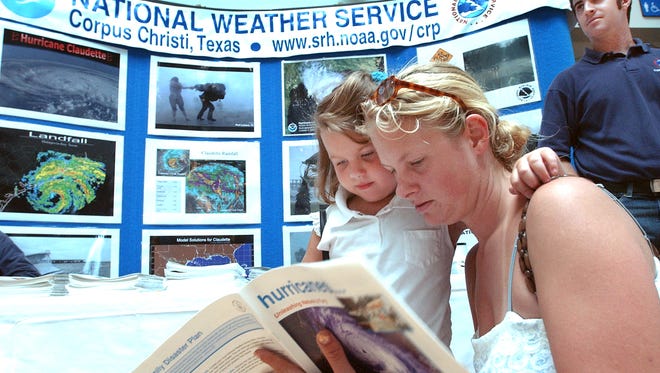 Megan Kelley and her daughter Elissa pick up some literature from the Weather service exhibit during the 12th. annual celebration of World Ocean Day at Texas State Aquarium in 2005.