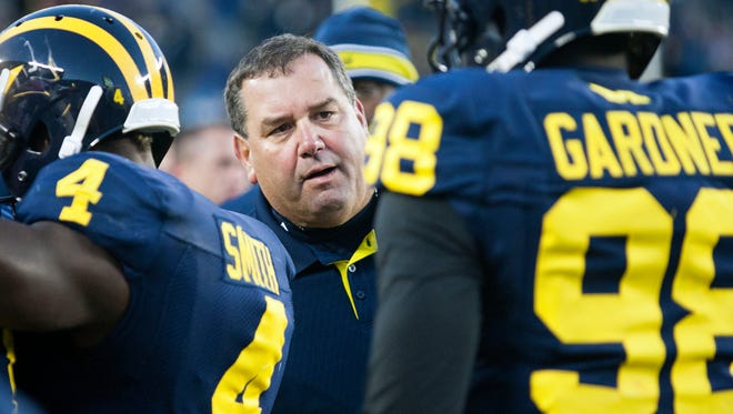 Michigan head coach Brady Hoke, center, talks with quarterback Devin Gardner (98) after a touchdown on the sideline in the fourth quarter of an NCAA college football game in Ann Arbor, Mich., Saturday, Nov. 1, 2014. Michigan won 34-10.