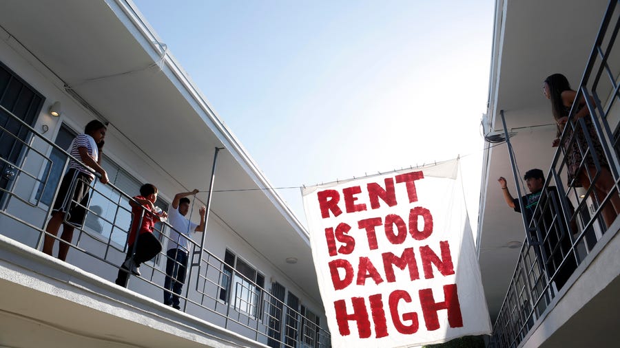 Organizers with Housing Long Beach, a local advocacy group pushing for rent control and eviction protections, hang up a sign in the courtyard of an apartment complex on Cedar Avenue.