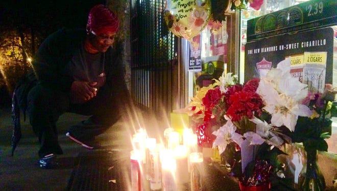 Wilma Jones lights a candle at a memorial site outside the Bull Market on Hollywood Drive. On Wednesday night, Jackson police said, a gas station clerk was shot and killed during a robbery at the store.