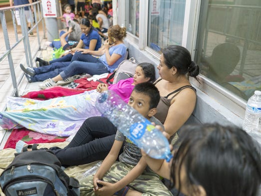 Migrants from Central America wait in line to ask for