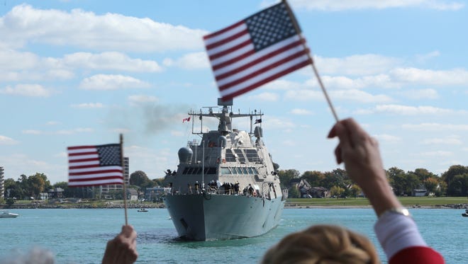 People watch as the USS Detroit, a Navy warship, is seen on the Detroit River as it arrives in Detroit on Friday, Oct. 14, 2016.