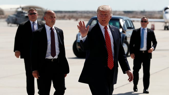 In this Tuesday, Aug. 22, 2017, file photo, President Trump walks with his Secret Service protective detail as he waves before he departs on Air Force One in Yuma, Ariz.