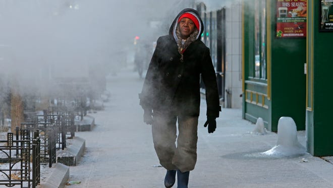 M.Z. Rose of Milwaukee walks through a plume of steam emitting from Mo's Irish Pub on W. Wisconsin Ave. near N. Plankinton Ave. Monday in Milwaukee. Milwaukee's average temperature between Christmas Day and New Year's Eve was 6.1 degrees, the coldest since 1880.