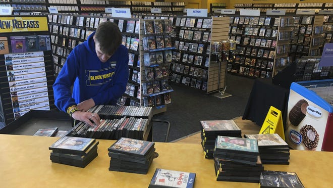 Employee Ryan Larrew alphabetizes returned movies before re-shelving them at the last Blockbuster store on the planet in Bend, Ore., on Tuesday, March 12, 2019. When a Blockbuster in Perth, Australia, shuts its doors for the last time on March 31, the store in Bend, Ore., will be the only one left on Earth, and most likely in the universe. (AP Photo/Gillian Flaccus)
