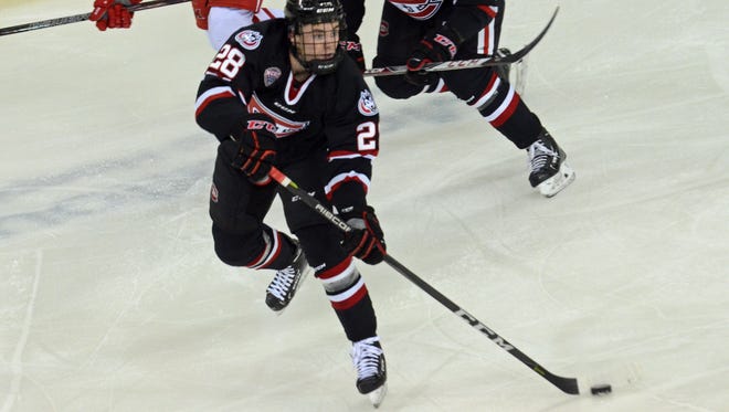 St. Cloud State's Kevin Fitzgerald (28) passes the puck with teammate Jon Lizotte (10) and Miami's Kiefer Sherwood in pursuit.  St. Cloud State beat Miami 4-0 for an NCHC series sweep Saturday in Oxford, Ohio.
