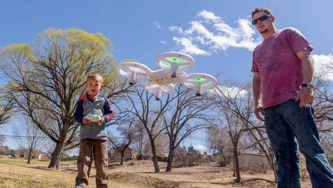 Five-year-old Logan Ward, left, plays with his new drone while his father, Brian Ward, looks on Monday at Brookside Park in Farmington.