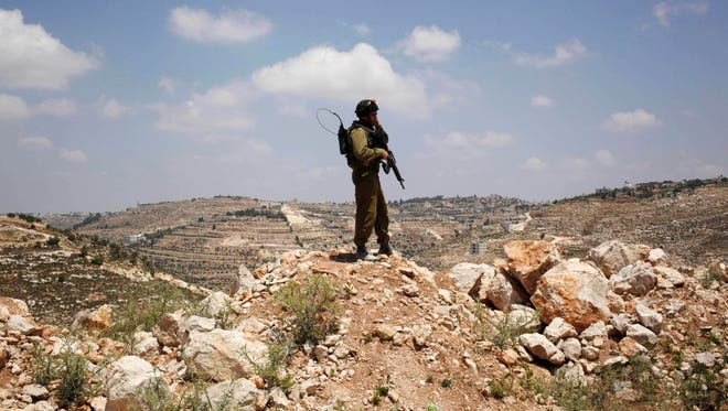 An Israeli soldier stands near the West Bank city of Hebron during a search for three missing teenagers from nearby settlements.