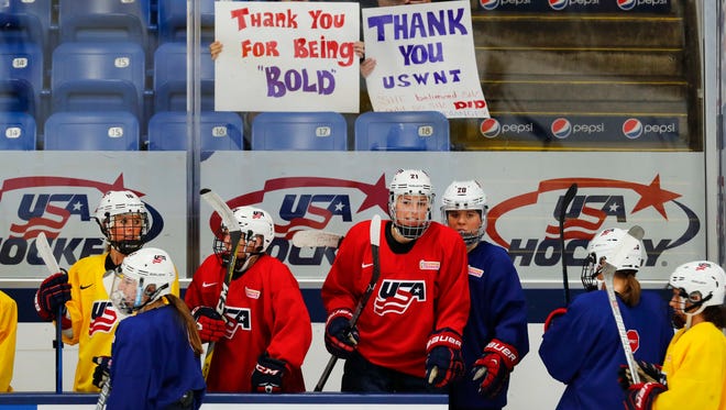 In this Thursday, March 30, 2017, photo, U.S. teammates practice with fans holding support signs in preparation for the IIHF Women's World Championship hockey tournament in Plymouth, Mich. USA Hockey and the women's national team agreed to a contract Tuesday, March 28 that ended a wage dispute. (AP Photo/Paul Sancya)