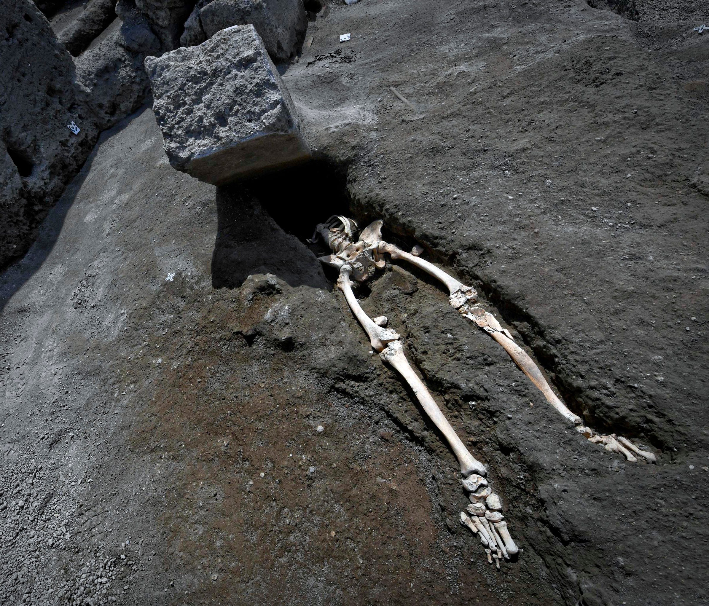 The legs of a skeleton emerge from the ground beneath a large rock believed to have crushed the victim's bust during the eruption of Mt. Vesuvius in A.D. 79, which destroyed the ancient town of Pompeii, at Pompeii's archeological site, near Naples, o