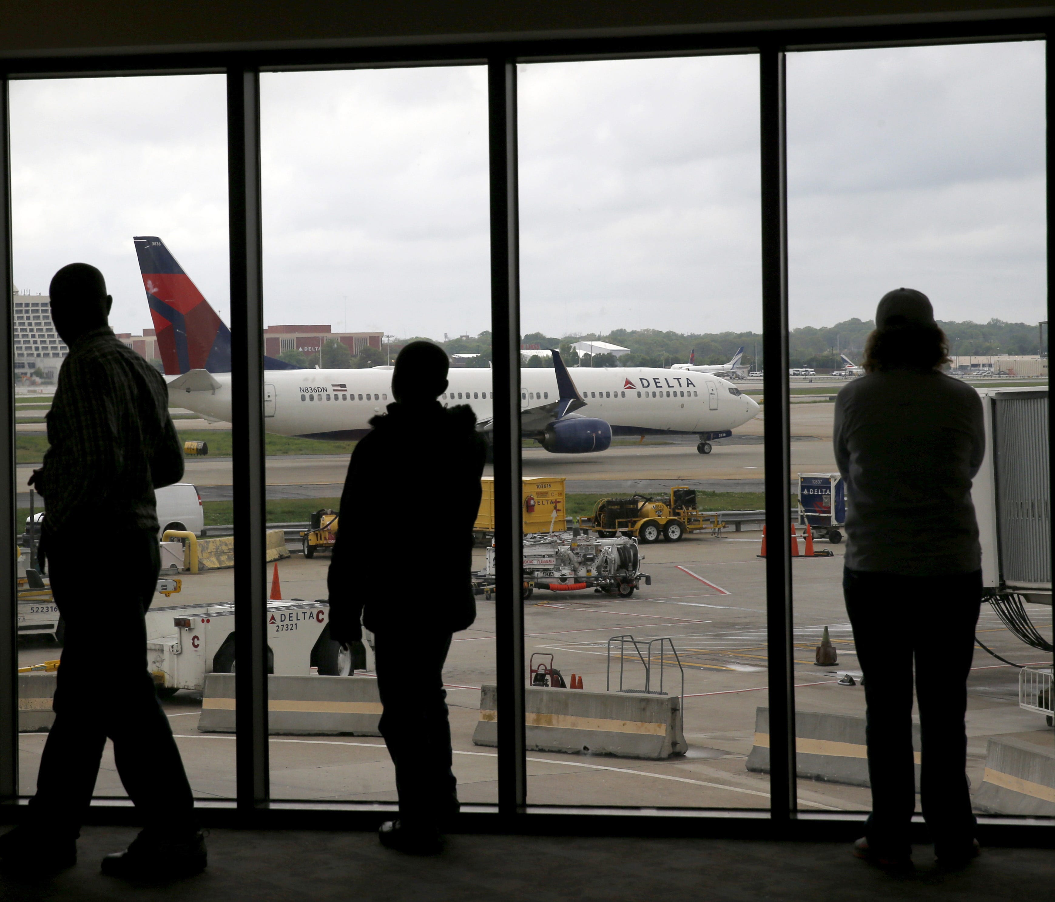 In this file photo from April 14, 2015, Delta Air Lines passengers watch as a Delta plane taxis at Atlanta's airport.