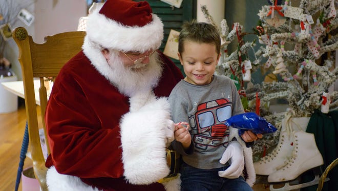 Joe Bartolacci, 5, receives a gift and a candy cane from Santa Friday night as Santa made a stop at Black Sheep Antique and Primitive Creations in downtown Marshall.