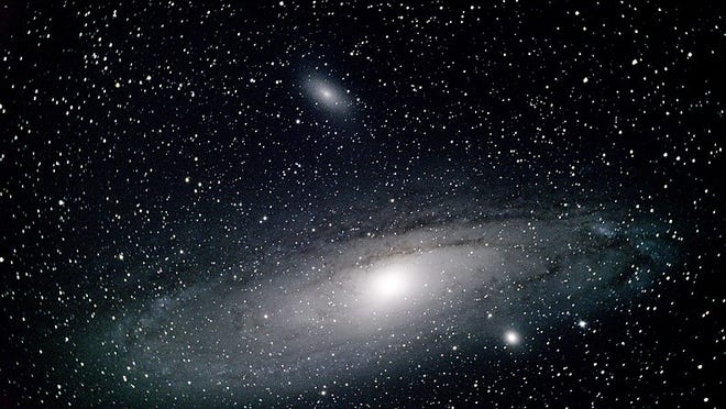 The Andromeda Galaxy, M31. The bright spot along its lower edge is satellite galaxy M32; above M31 as seen here is its satellite, M110. A small telescope will show the satellites. [Photo by Parker Bossier (Own work) [CC BY-SA 4 (https://creativecommons.org/licenses/by-sa/4)], via Wikimedia Commons]