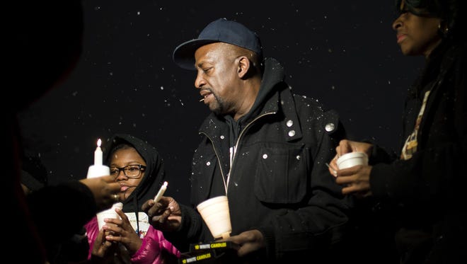 From left, Tamylia Wallace, 13, Alfred Daniel and his wife, Bridget Hopson, light candles during a vigil for Daniel and Hopson's daughter, Kiah Hopson, who was fatally shot at the Parkside East Apartments in Sterling Heights.