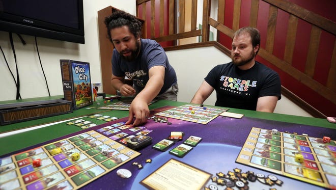 Isaias Valdez III, left, plays Dice City with Stockpile Games co-owner Justin Schnell at the store on Thursday, July 28. The shop has recently moved to a new location on South Eighth Street for more space.