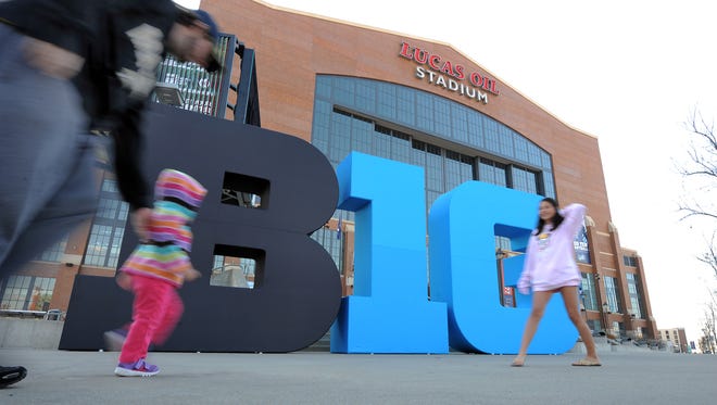 Big Ten football fans walk by the Big Ten logo out front of Lucas Oil Stadium Friday afternoon in preparation for this the Big Ten football championship game Saturday evening. The Big Ten Fan Fest will also be open Saturday from 10 a.m. to 8 p.m. Matt Kryger / The Star