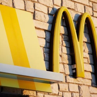 The outside of a McDonald's restaurant, with a close-up shot of the golden arches logo on the side of the building.