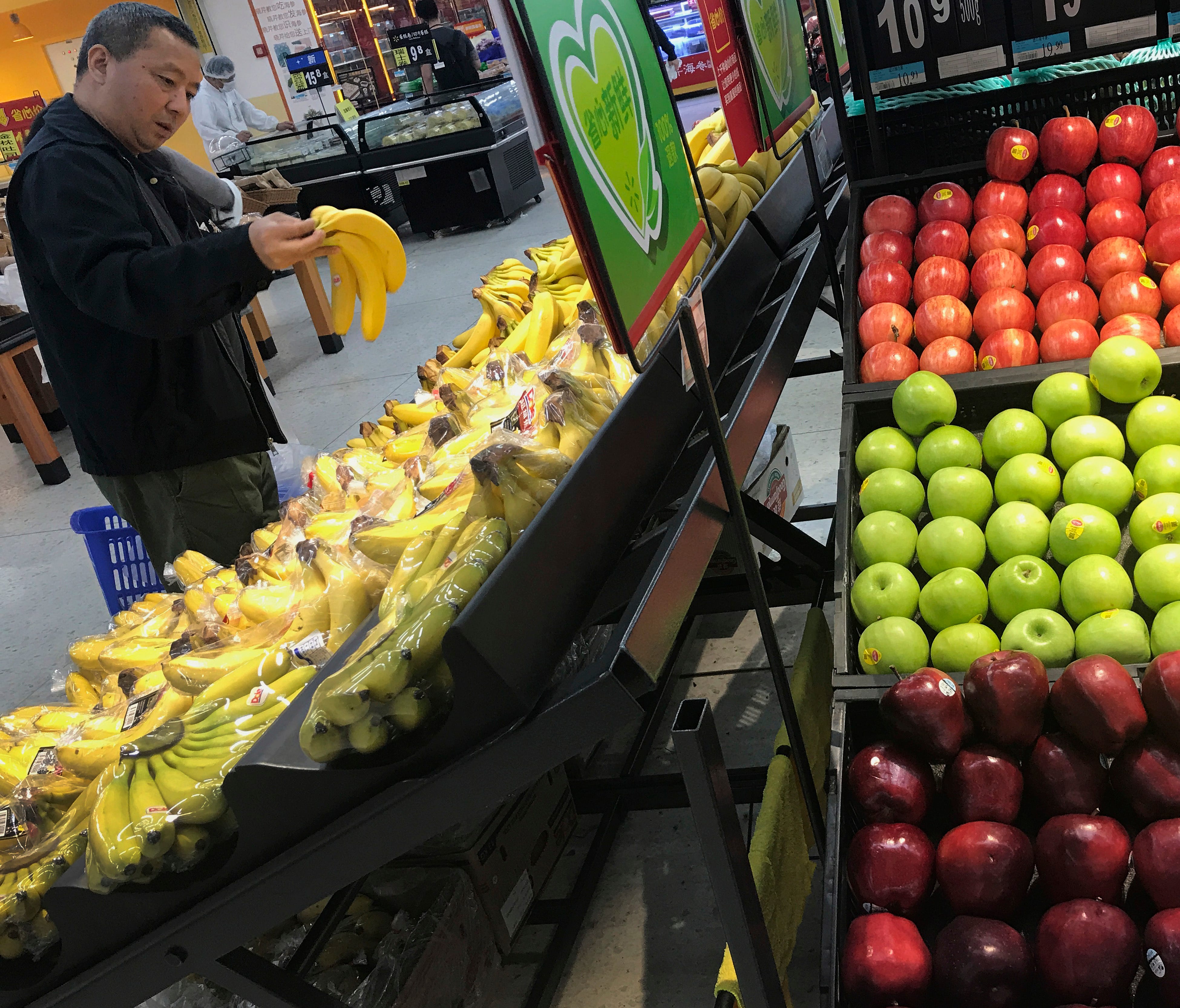 A man chooses bananas near imported apples from the United States at a supermarket in Beijing on Monday.