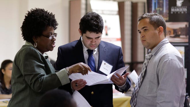 In this Friday, Jan. 23, 2015 photo, instructor Lavinda Young, left, helps Fabian Perez, center, and Lazaro Chaviano, right, with their resumes during a job fair at the Hospitality Institute, in Miami. The U.S. Labor Department reports on the number of people who applied for unemployment benefits for the week ending Jan. 24 on Thursday, Feb. 5, 2015. (AP Photo/Lynne Sladky)