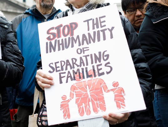 Image shows protester holding a sign reading "stop the inhumanity of separating families"