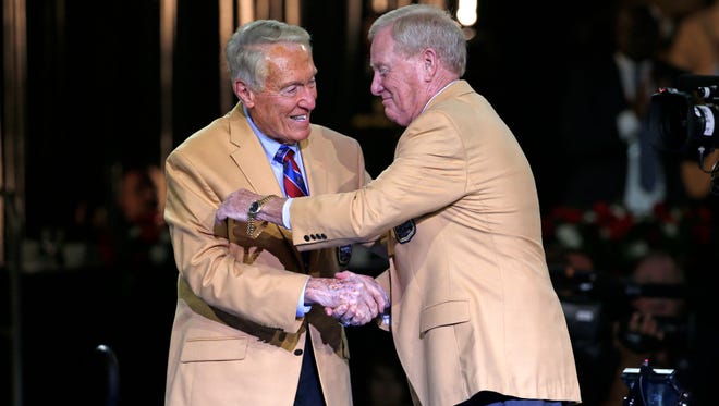 Pro Football Hall of Fame inductee Bill Polian slips into his gold jacket with help from his presenter, Hall of Fame coach Marv Levy, during the Gold Jacket Ceremony in Canton, Ohio, August 6, 2015.