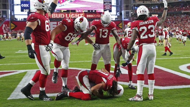 Cardinals receiver Larry Fitzgerald cradles the game- winning catch against the 49ers in overtime 
in Glendale on Sunday.