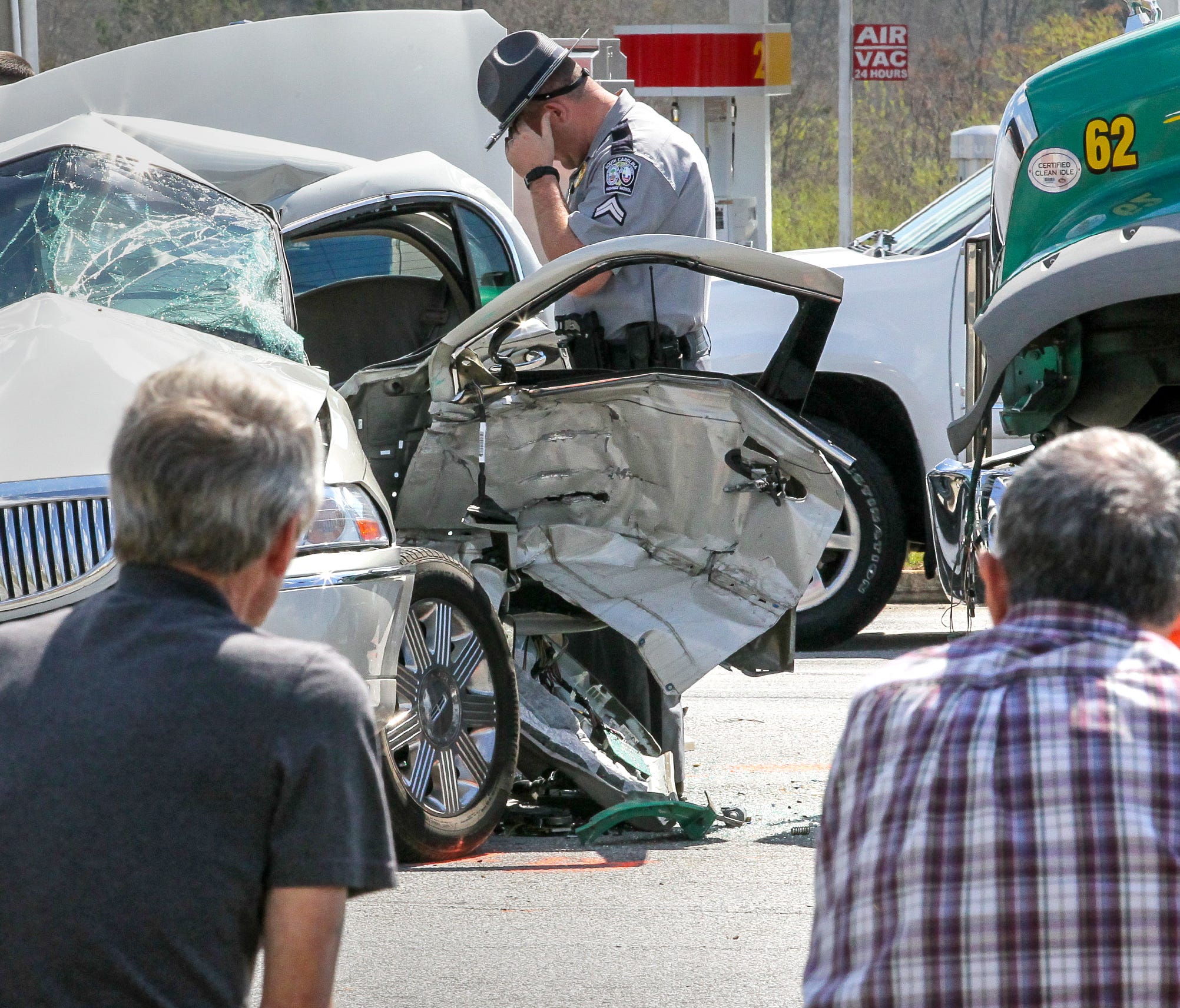 A South Carolina Highway Patrol officer looks over the scene of a wreck Friday afternoon at S.C. 24 and Whitehall Road. A Mack truck from Powell's Trash Services collided with a beige Lincoln Continental shortly after noon. The truck driver, left, wa