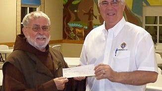 Shown is Pastor Friar Aubrey McNeil of St. Mary of the Angels Catholic Church, as he accepts the check from activity representative Michael Massey.
