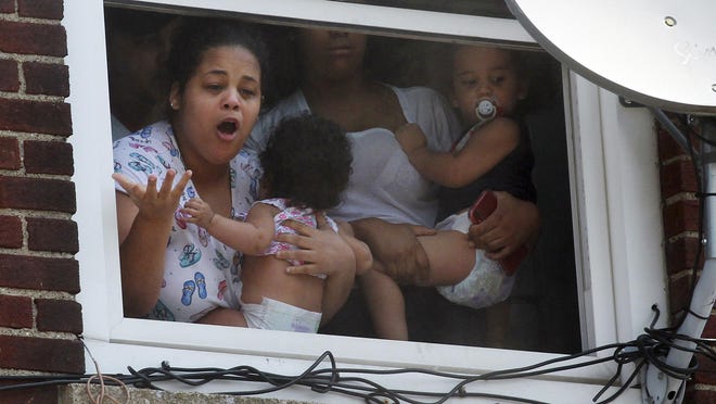 Women and children wait for help after a fire broke out inside their building in Hazleton, Pa., Friday, July 26, 2019. City firefighters used an aerial truck to rescue occupants from the third floor of the building. Prestigio Restaurant and apartments were damaged by the fire. (Warren Ruda/Hazleton Standard-Speaker via AP)