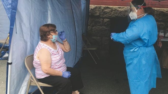 A Seven Hills Behavioral Health team member gets ready to perform a free Covid-19 test on a woman at the Immigrants' Assistance Center in New Bedford on Monday.