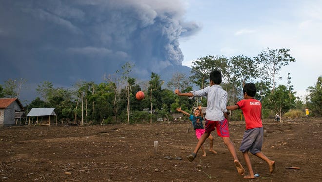 Balinese children play soccer as the Mount Agung volcano spews volcanic ash in Karangasem, Bali, Indonesia on Nov. 26,  2017. 