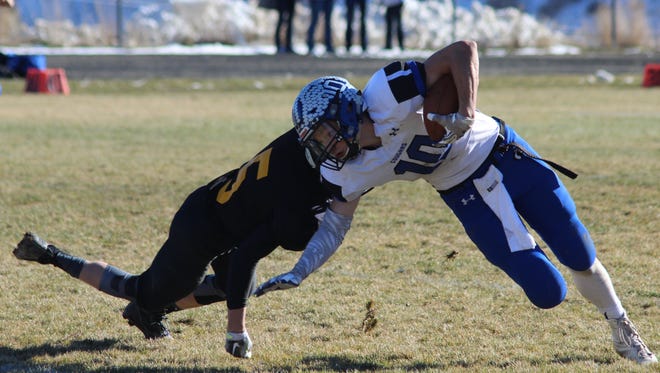 Resurrection Christian senior wide receiver Luke Fick fends off a Meeker defender Saturday in Meeker. The Cougars rolled to a 48-6 victory to advance to the Class 1A semifinals against Paonia.