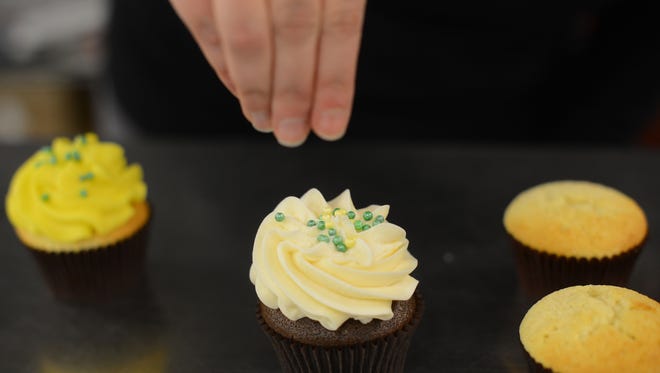 Michelle Axford of The Cupcake Couture in De Pere decorates green and gold cupcakes for weekend parties built around Sunday's NFC Championship game.