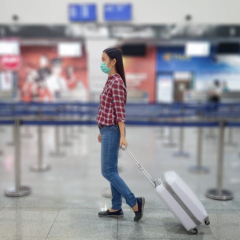 A traveler wearing a mask walks through an airport