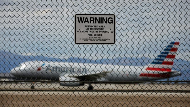 In this May 17, 2016, file photo, a sign warns against trespassing as a plane lands at McCarran International Airport in Las Vegas. While intruders routinely breach the security fences protecting runways and planes at U.S. airports, the federal Transportation Security Administration is not keeping up with the threat or doing enough to help airports identify their vulnerabilities, according to a government report released Tuesday, May 31, 2016.