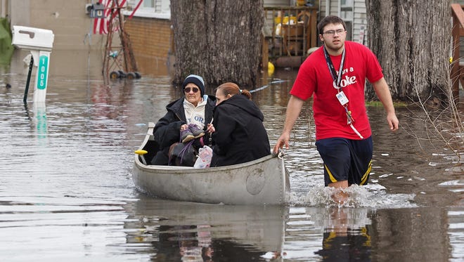 Garry Clark, 15, uses a canoe to take his grandmother Jeanne Kendall and June Wedl from their flooded home Thursday, Feb. 22, 2018 in Comstock's Lakewood neighborhood. Severe and record-breaking flooding is predicted for the Kalamazoo River at Comstock, the National Weather Service Grand Rapids said Thursday.
