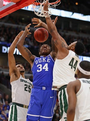 Wendell Carter Jr. of the Duke Blue Devils loses control of the ball under pressure from Kenny Goins and Nick Ward of the Michigan State Spartans.