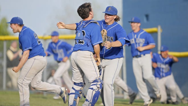 Hamilton pitcher Jacob Baker (5), right, who earned the win, celebrates with Ryan Robinson (12), left, who hit a two-run single in the seventh inning, after the 3-1 win against St. Xavier at St. Xavier High School.