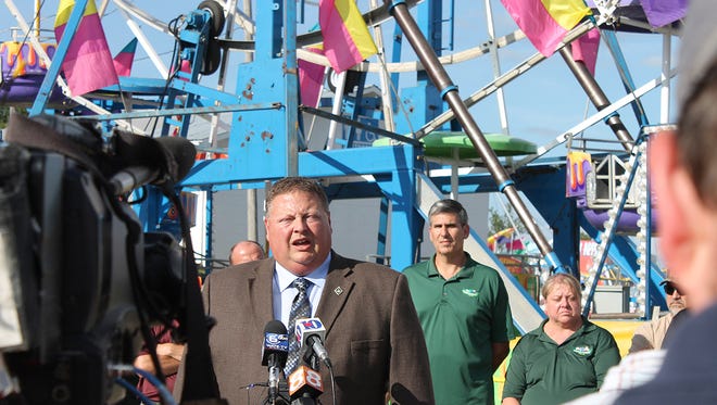 Greeneville Police Detective Capt. Tim Davis answers questions at the foot of the Ferris wheel at the Greene County Fair Tuesday, Aug. 9, 2016,  during a press conference. Members of the Greene County Fair Board of Directors stand behind him.