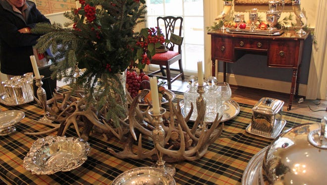 Staffer Suzy Askew examines the deer antlers and silver pieces on the dining table at Dixon Gallery and Gardens. The theme for this year's holiday decorations is "Tis Open Season: Fa-la-la-la-la."
