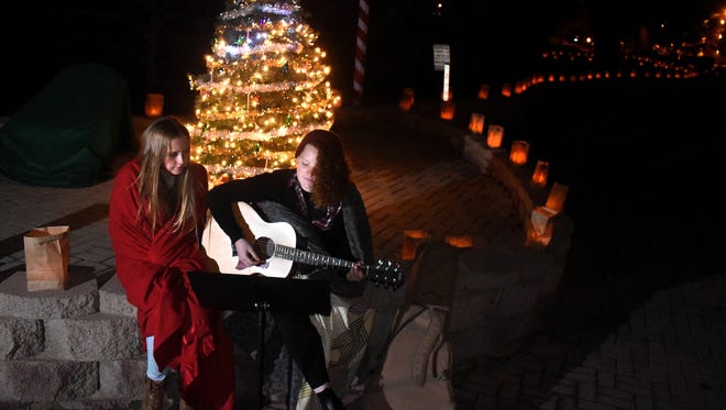 Rachel Carlson, 16, left, and Faith Chavers, 16, sing Christmas carols during Riverglo on Friday at Berg Park.