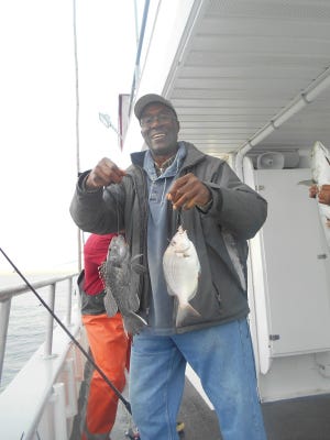An angler on the Capt. Cal II with a double-header catch of a sea bass (left) and porgy.