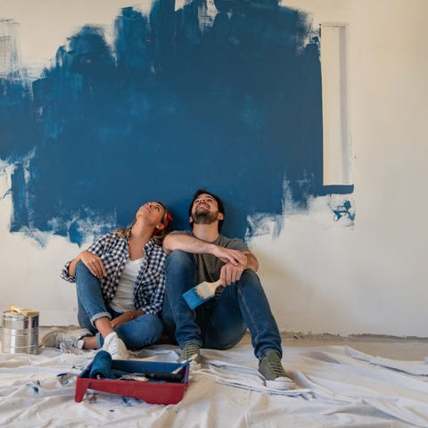Two people resting from painting wall in empty hom