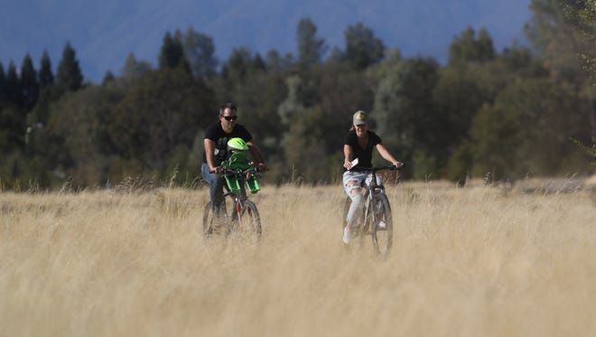 Kevin Bushnell, his son Wyatt, 8 months, and wife Katlynn rides bikes Monday at Clover Creek Preserve in Redding.