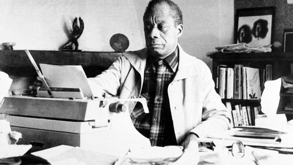 American novelist James Baldwin sits in front of h